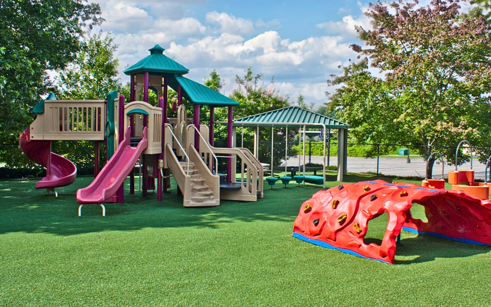 Commercial playground on turf with green and purple playset